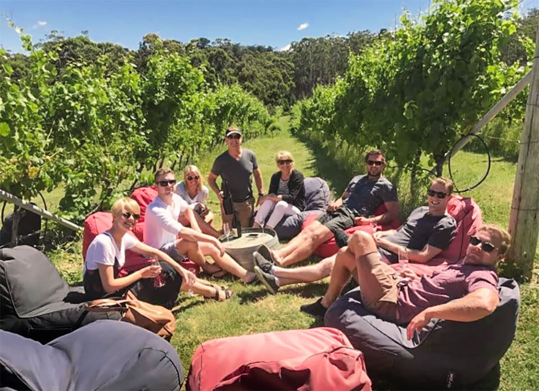 Group of people sitting enjoying wine in a vineyard